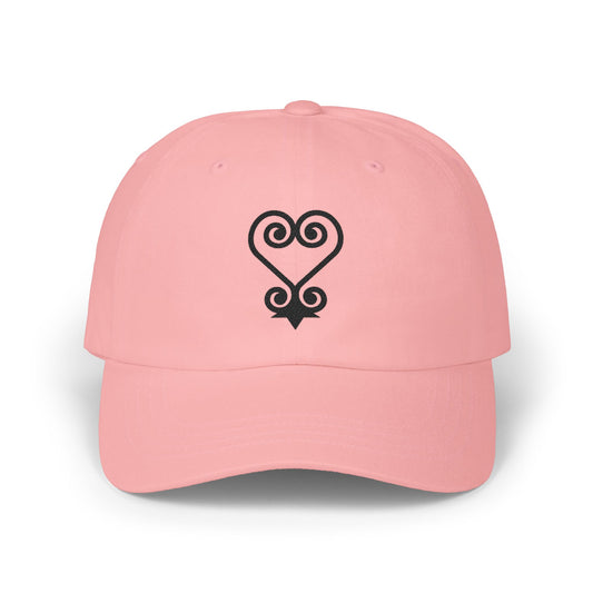 Pink baseball cap with black Sankofa heart symbol embroidered on front.