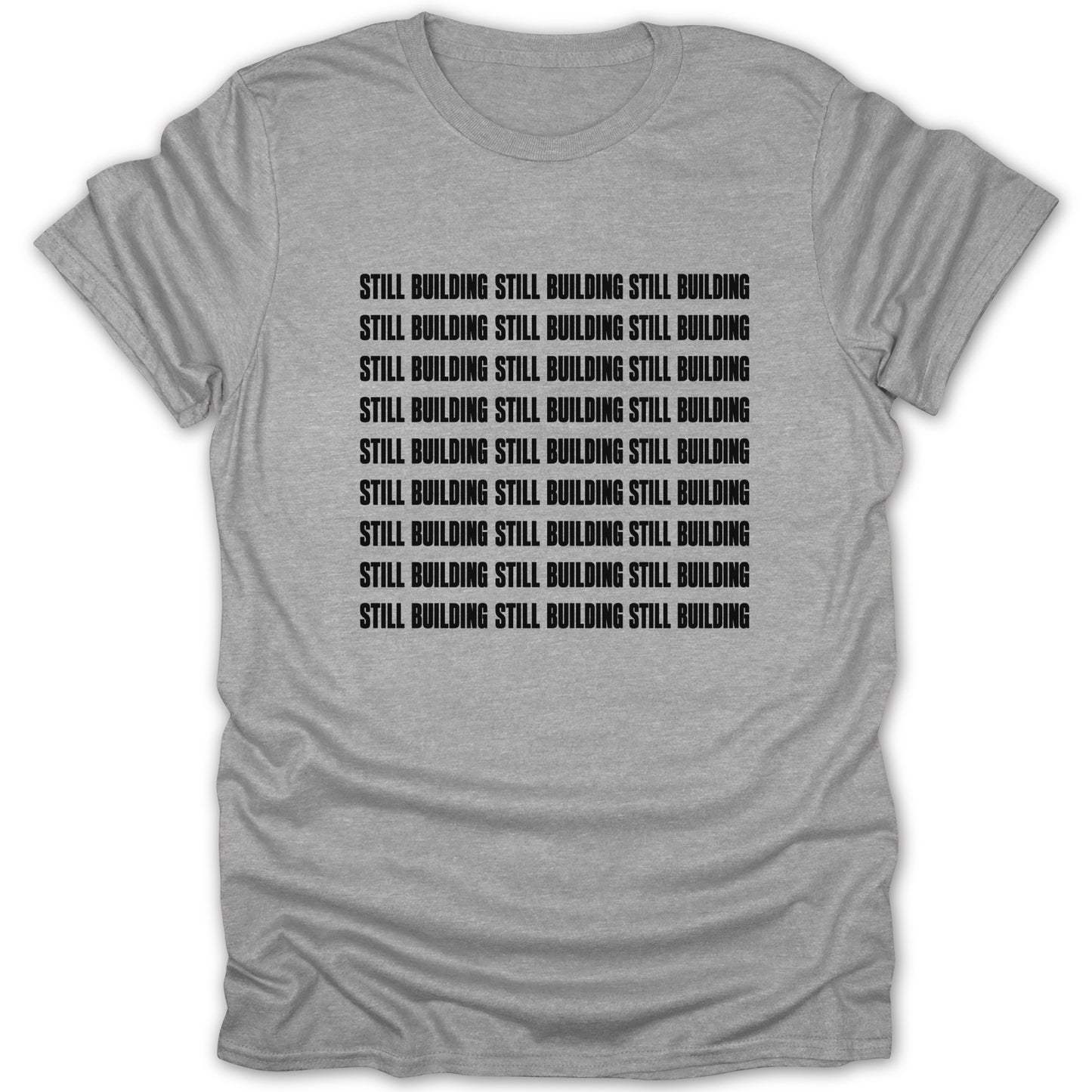 Grey t-shirt with black text repeating "STILL BUILDING STILL BUILDING STILL BUILDING".