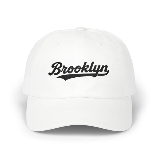 White baseball cap with "Brooklyn" in black script lettering.