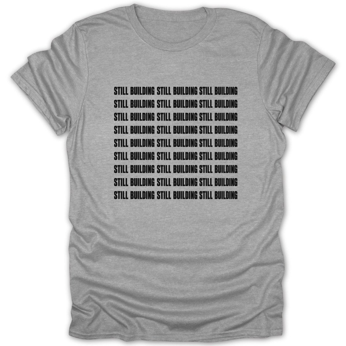 Grey t-shirt with black text repeating "STILL BUILDING STILL BUILDING STILL BUILDING".