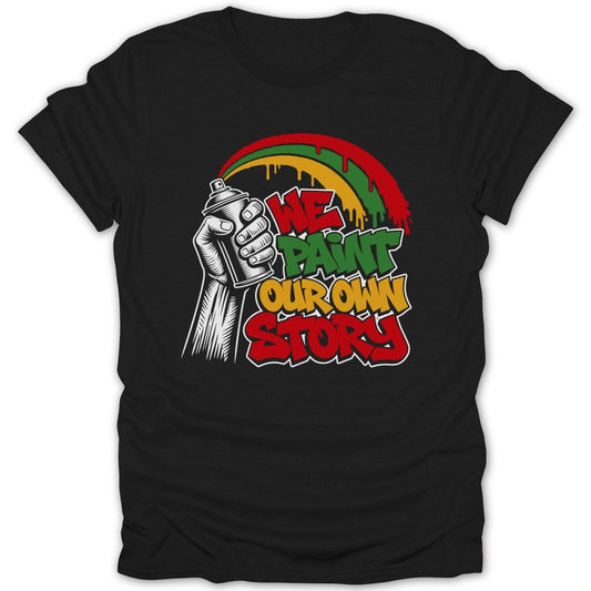 Black t-shirt with "We Paint Our Own Story" graffiti-style text and rainbow.