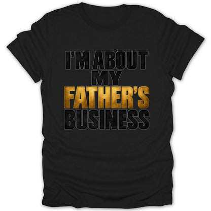 Black t-shirt with gold and black text that reads "I'M ABOUT MY FATHER'S BUSINESS".