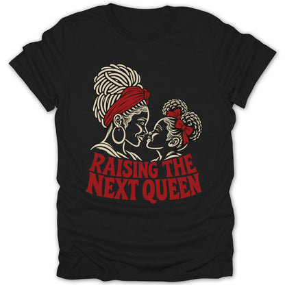 A black short-sleeved t-shirt featuring a cream and red graphic of a mother and daughter facing each other with the text "Raising the Next Queen" below them.
