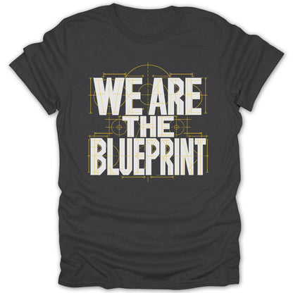 Dark grey t-shirt with white text "WE ARE THE BLUEPRINT" overlayed on a blueprint design.