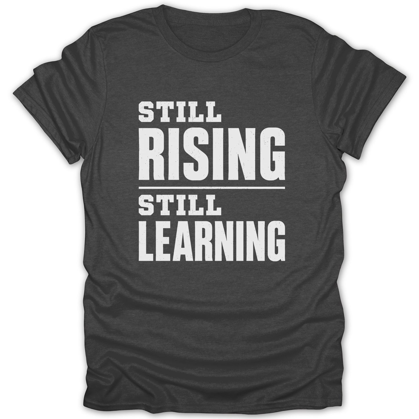 Dark gray t-shirt with white text reading "STILL RISING STILL LEARNING".