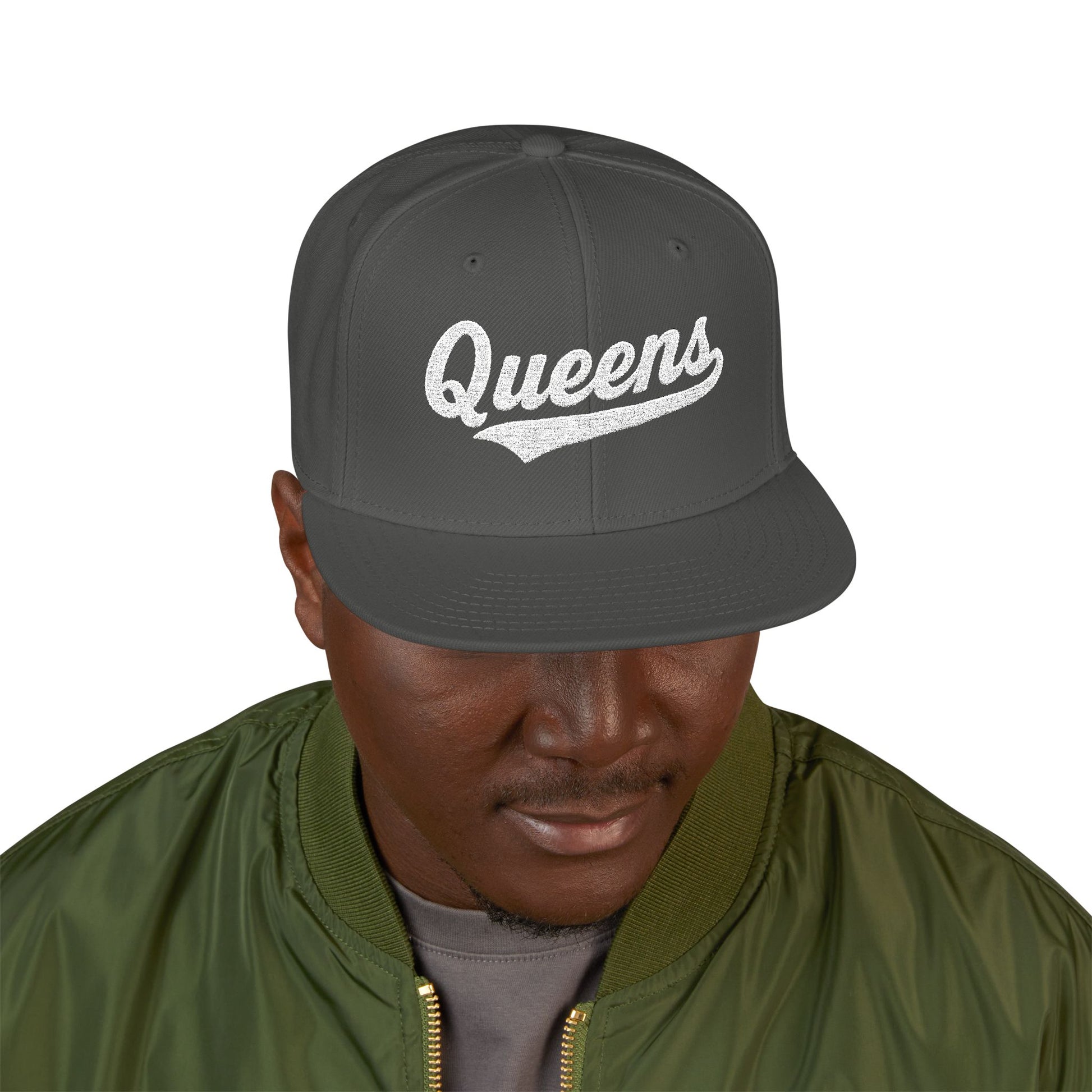 Gray baseball cap with white "Queens" text, worn by a man.