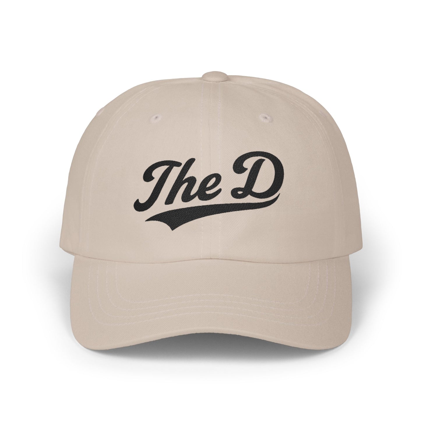 Cream baseball cap with "The D" embroidered in black cursive lettering.