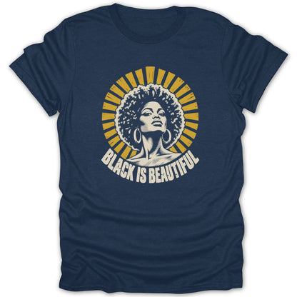 Dark blue t-shirt featuring a retro graphic of a Black woman with an afro and hoops under yellow sun rays, with text reading Black Is Beautiful.