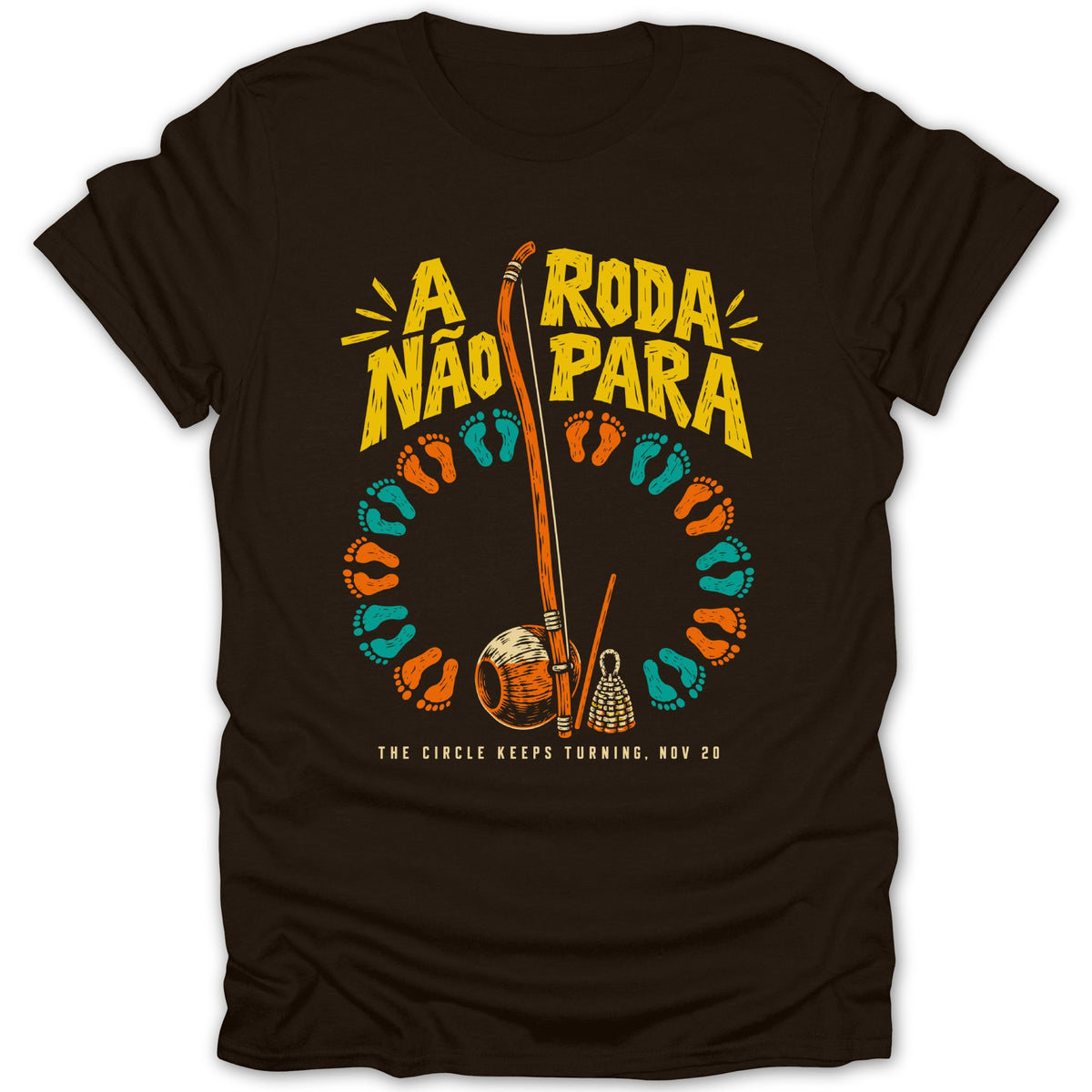 Brown t-shirt with "A Roda Não Para" text and capoeira instruments.