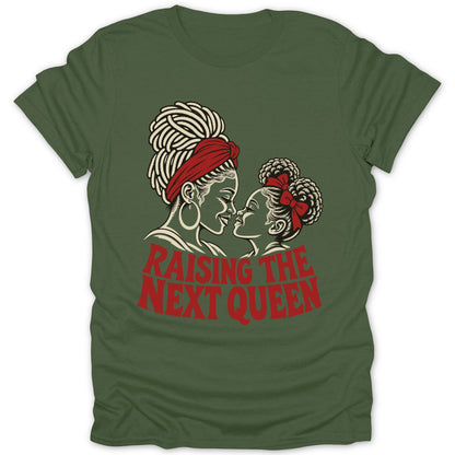 Olive green t-shirt with a graphic of a Black mother and daughter facing each other, with the red text "RAISING THE NEXT QUEEN".