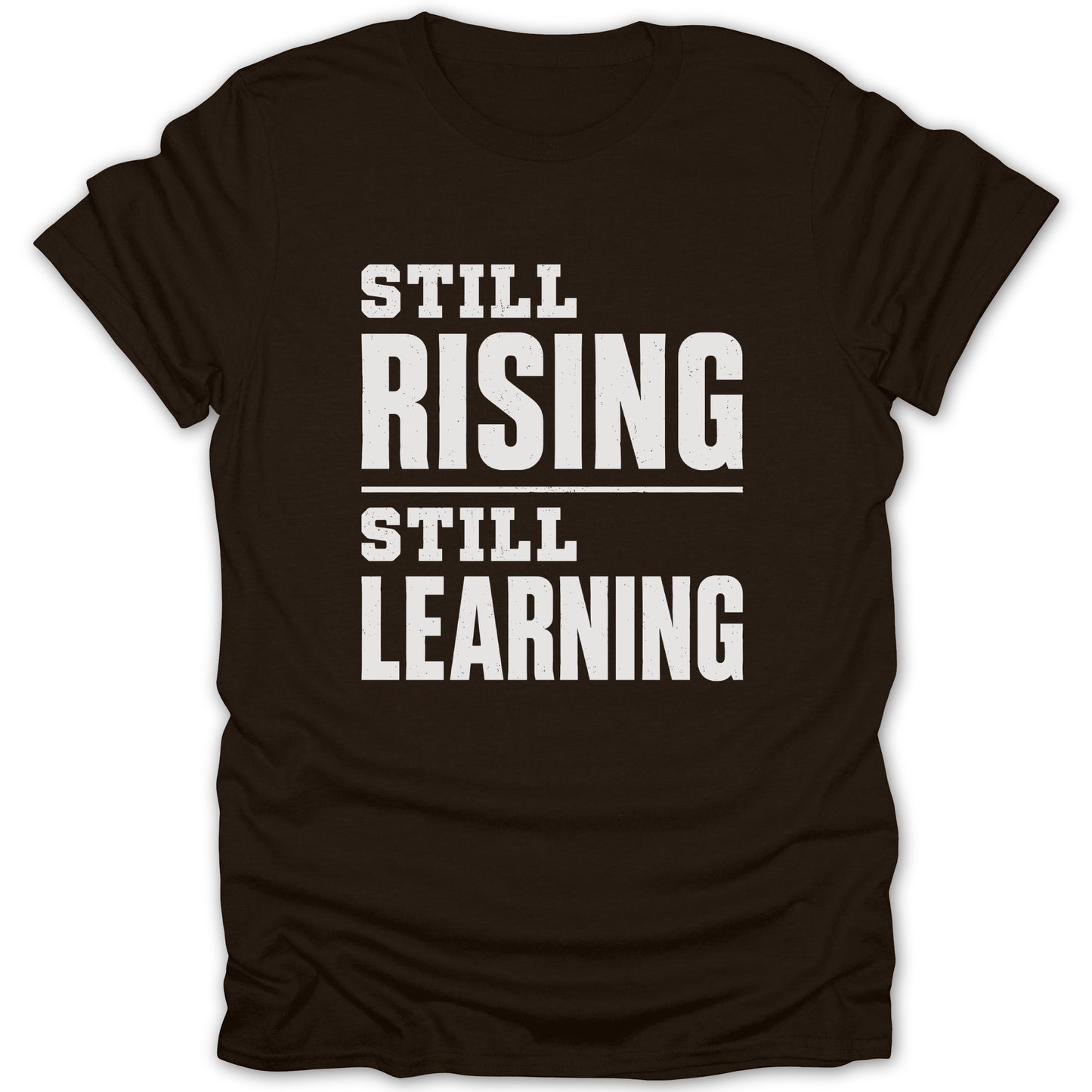 Brown t-shirt with white text reading "STILL RISING STILL LEARNING".
