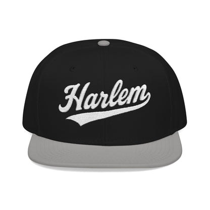 Black snapback hat with "Harlem" in white script embroidered on the front.