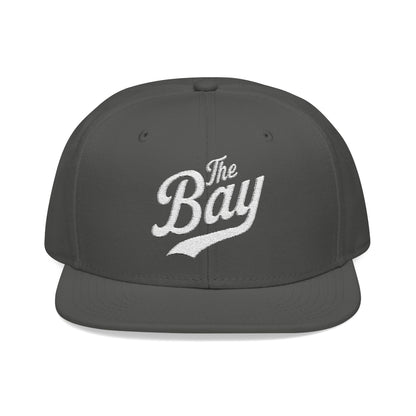 Charcoal snapback hat with white embroidered "The Bay" text.