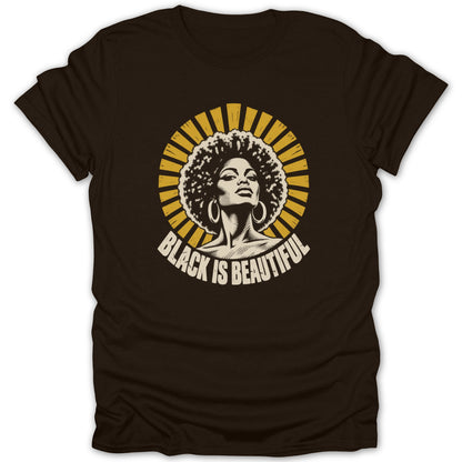 A dark brown t-shirt featuring a yellow graphic of a Black woman with an afro and hoops, accompanied by the text "Black Is Beautiful".