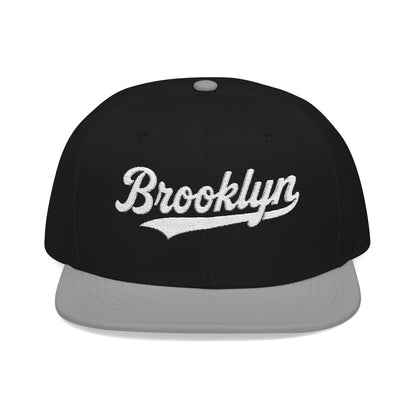 Black flat brim hat with "Brooklyn" embroidered in white script.