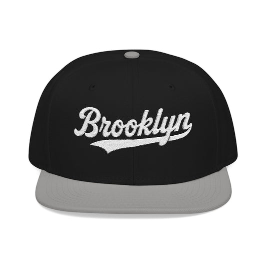 Black flat brim hat with "Brooklyn" embroidered in white script.