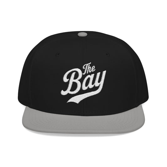 Black snapback hat with "The Bay" embroidered in white script on the front.