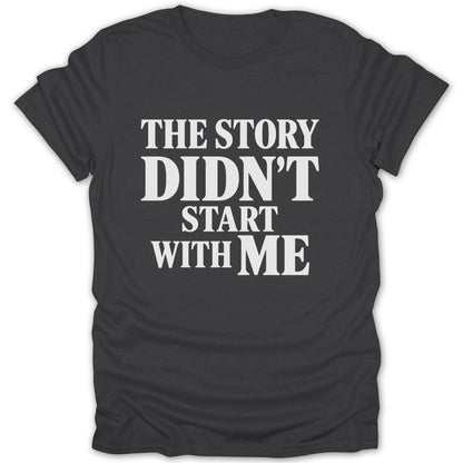 A dark gray t-shirt with white text reading THE STORY DIDN'T START WITH ME centered on the chest.
