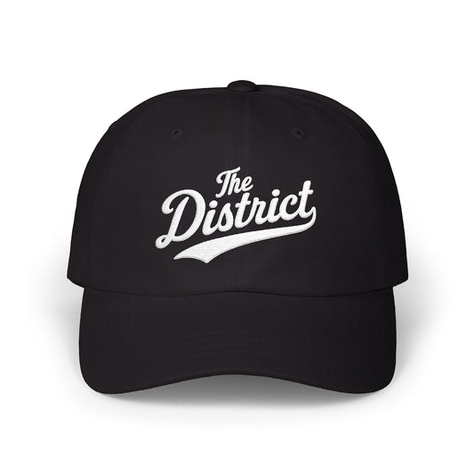 Black baseball cap with "The District" in white cursive embroidery.