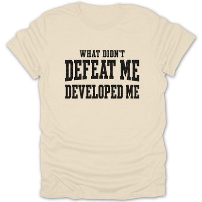 Cream t-shirt with black text that reads "WHAT DIDN'T DEFEAT ME DEVELOPED ME"