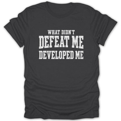 Dark gray t-shirt with white distressed text: "WHAT DIDN'T DEFEAT ME DEVELOPED ME".