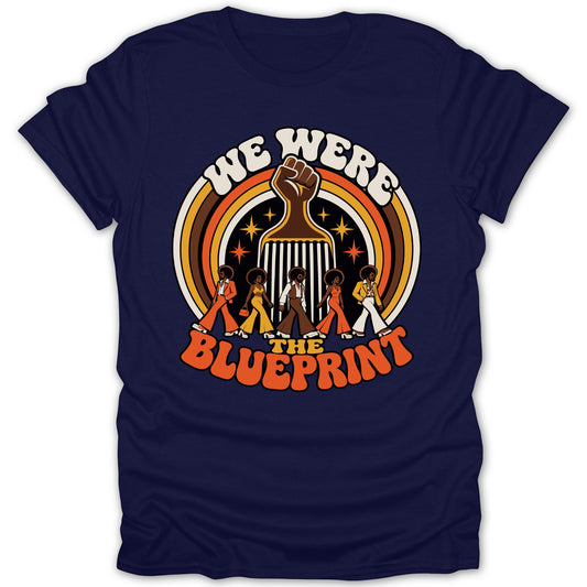 "We Were The Blueprint" text with raised fist and figures on a navy t-shirt.