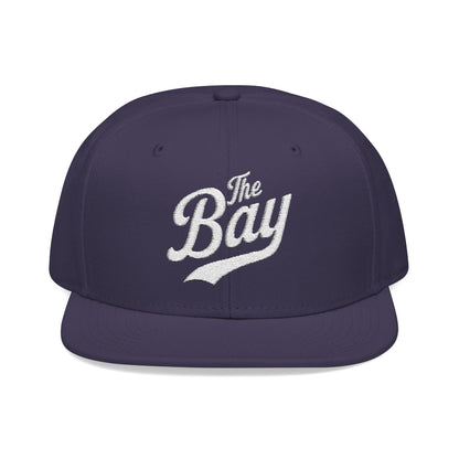Purple snapback hat with "The Bay" embroidered in white script.