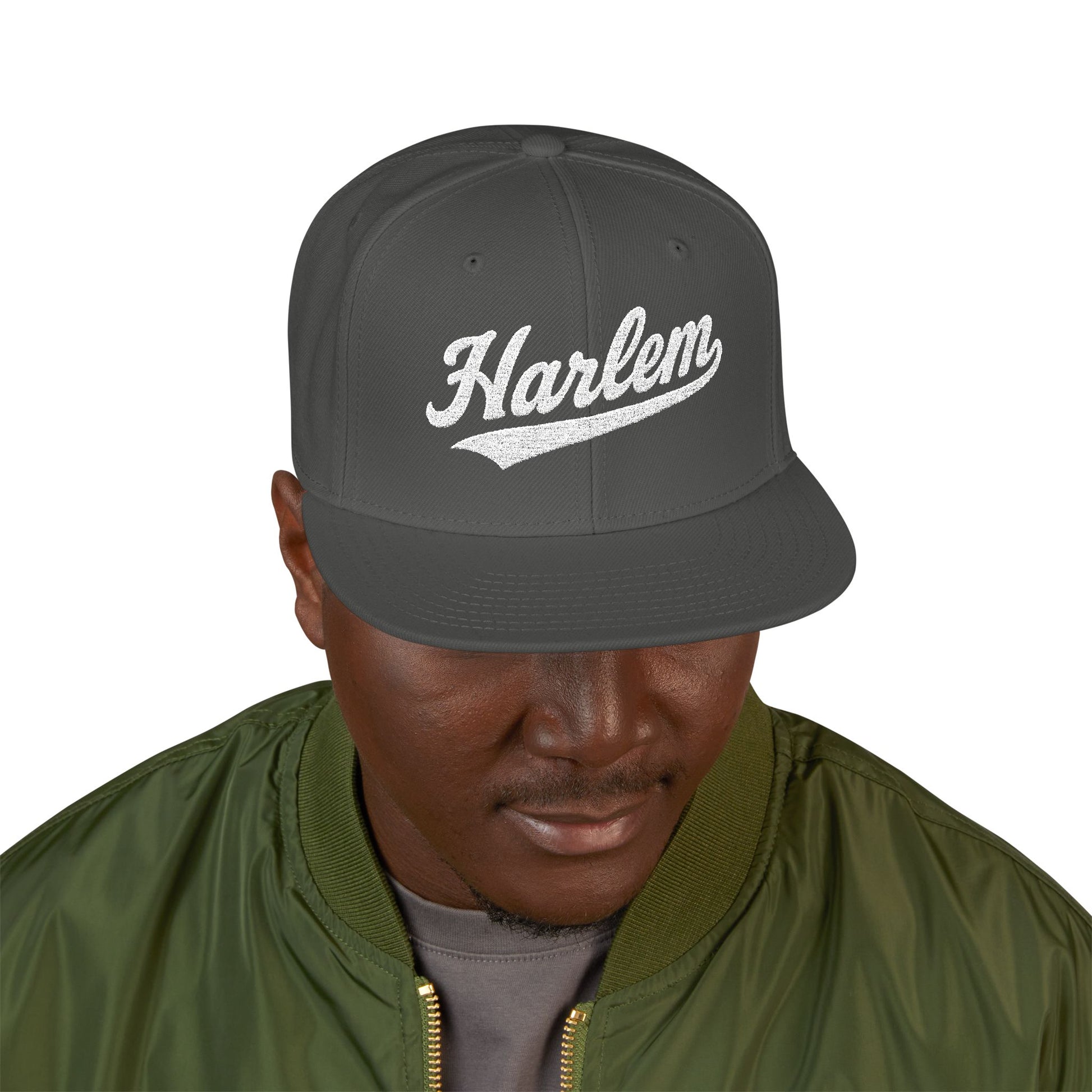 Dark gray snapback hat with "Harlem" in white cursive text.