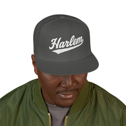 Dark gray snapback hat with "Harlem" in white cursive text.