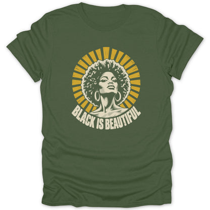 An olive green t-shirt with a vintage-style graphic of a Black woman with an afro and hoop earrings, surrounded by yellow sunburst rays and the text Black Is Beautiful.
