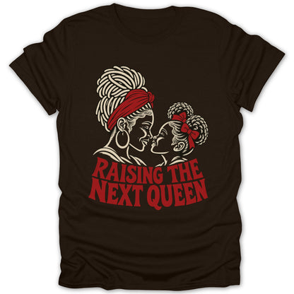 Dark brown t-shirt featuring a cream and red illustration of a mother and daughter facing each other, with the text "RAISING THE NEXT QUEEN".