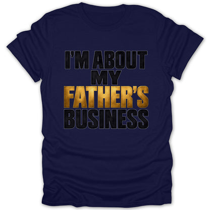 Navy t-shirt with gold and black text reading "I'M ABOUT MY FATHER'S BUSINESS."