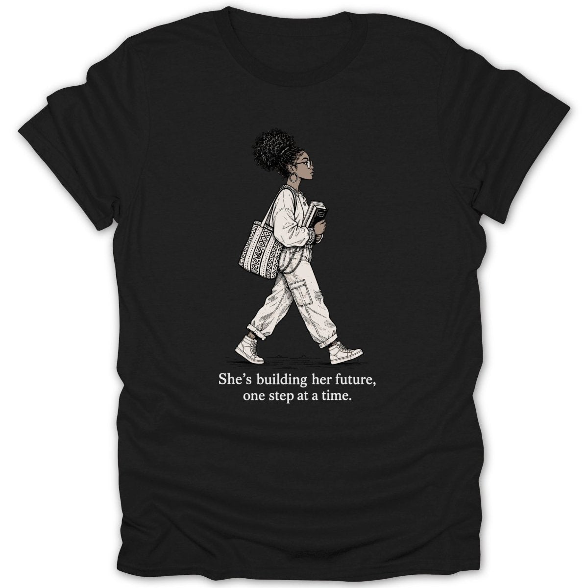 Black t-shirt with illustration of a woman walking and text "She's building her future, one step at a time."