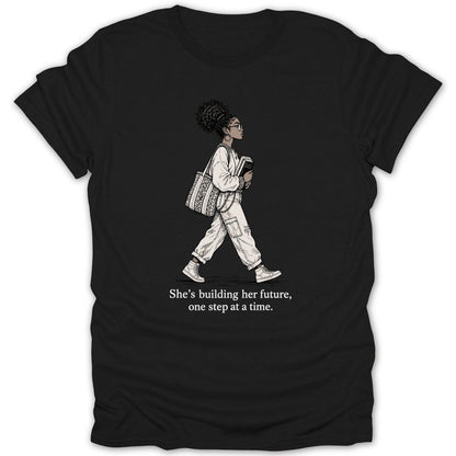 Black t-shirt with illustration of a woman walking and text "She's building her future, one step at a time."