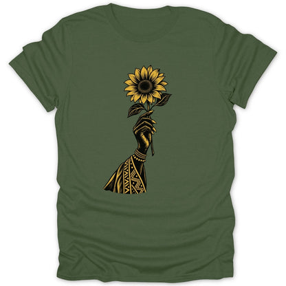 Hand holding a sunflower with tribal patterns on sleeve on green t-shirt.