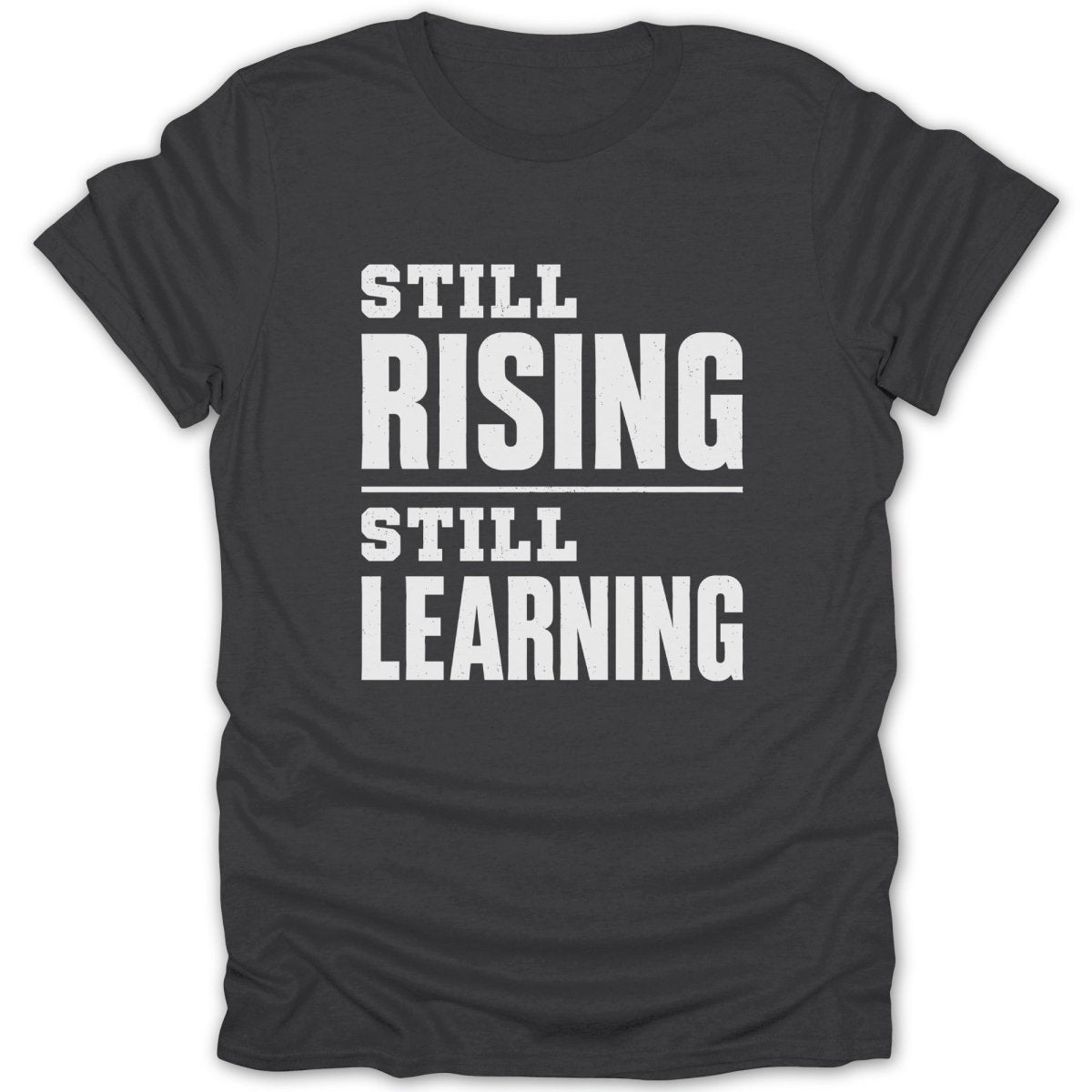 Dark t-shirt with white text "STILL RISING STILL LEARNING"