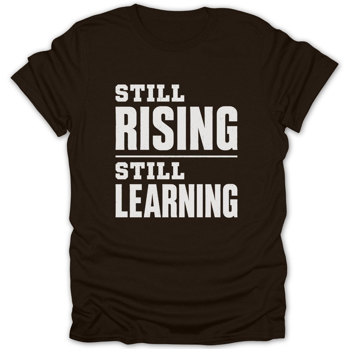 Brown t-shirt with white text reading "STILL RISING STILL LEARNING".
