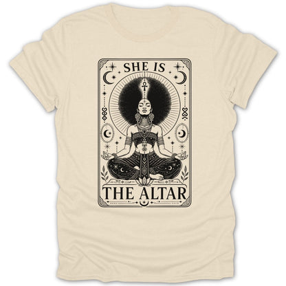 A woman with a large afro meditates on a shirt with text "SHE IS THE ALTAR".