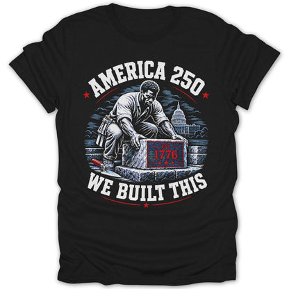 Black t-shirt graphic with man laying stone labeled "EST. 1776", texts "AMERICA 250" and "WE BUILT THIS".