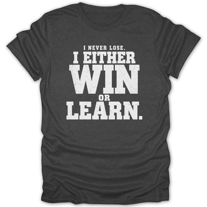 Dark grey t-shirt with white text: "I NEVER LOSE. I EITHER WIN OR LEARN."